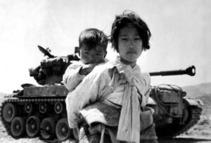 a famous photo of a young girl carrying an infant in front of a tank during the korean war